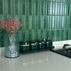 Green stacked tile backsplash on a kitchen counter with a glass vase of dried flowers and green canisters