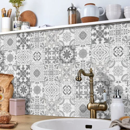 Grey and white patterned tile stickers as a kitchen backsplash behind a brass tap and white sink