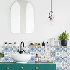 Blue and white patterned tile stickers behind a white vessel basin on a green bathroom vanity