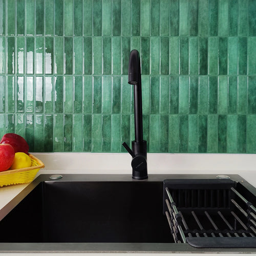 Green vertical stacked tile backsplash above a black kitchen sink with a matte black tap