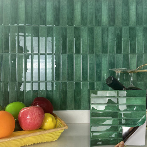 Green vertical peel-and-stick tile sheet being peeled off its backing in front of a tiled kitchen wall